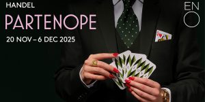 A vibrant sunset casts orange and pink hues over a calm sea, with silhouettes of distant hills.