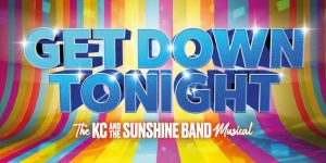 A lively dance floor with people in colourful outfits dancing under vibrant lights and a disco ball.