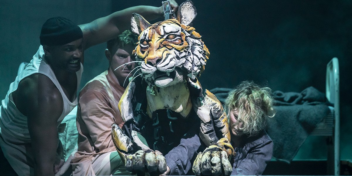 Habib Nasib Nader and Tom Larkin pose together, wearing costumes, with a tiger head backdrop.