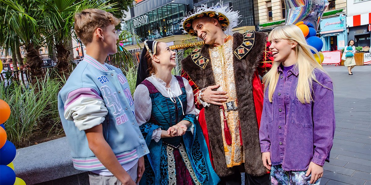 Two children stand either side of two people wearing Tudor outfits