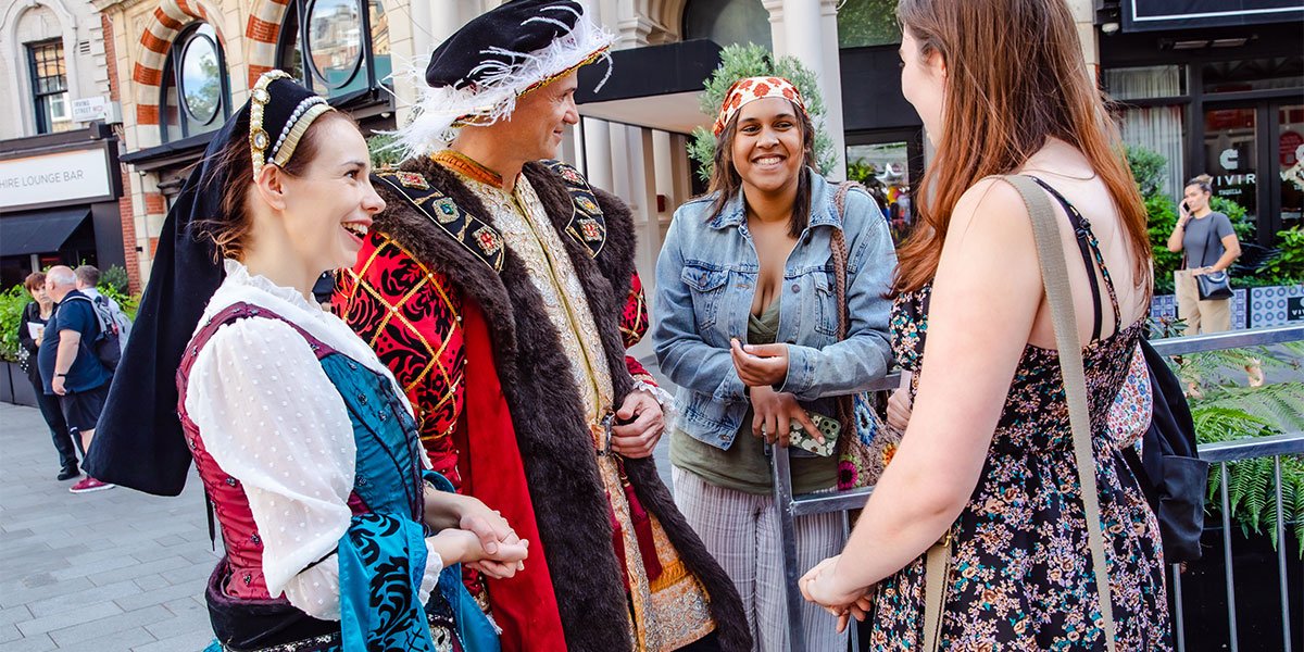 Two people dressed in Tudor costumes chat to two people in modern dress