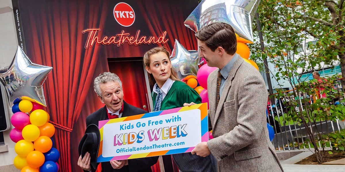 Three people dressed in 40s style clothing hold a sign reading 'Kids go free with Kids Week'