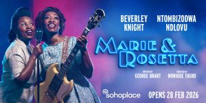 Two women in elegant dresses perform on stage, surrounded by warm lighting and a dark backdrop.