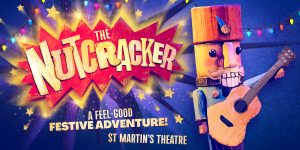 A decorative nutcracker figure in a red and gold uniform stands on a wooden surface, surrounded by festive decorations.