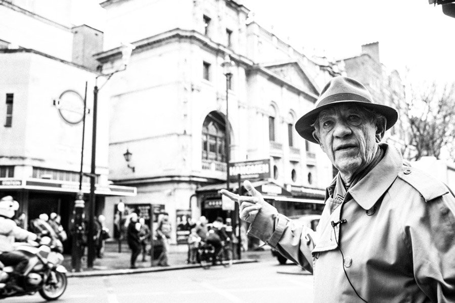 Ian McKellen recording the Official London Theatre Audio Tour, seated with a microphone, surrounded by studio equipment.