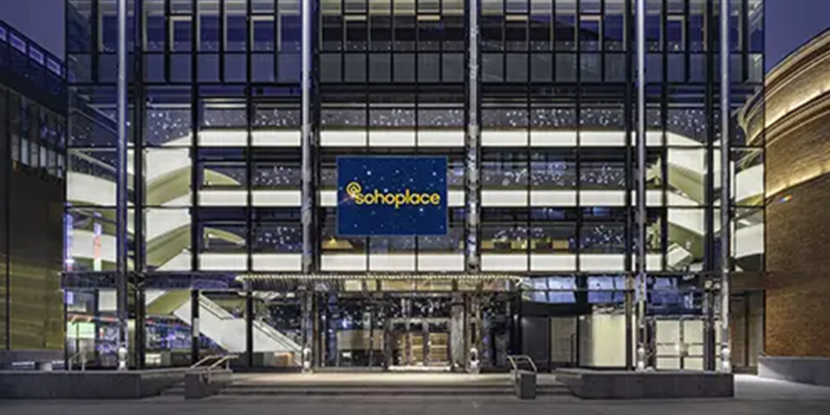 A vibrant theatre stage with bright lights, featuring a performer in a dynamic pose, surrounded by colourful set designs.